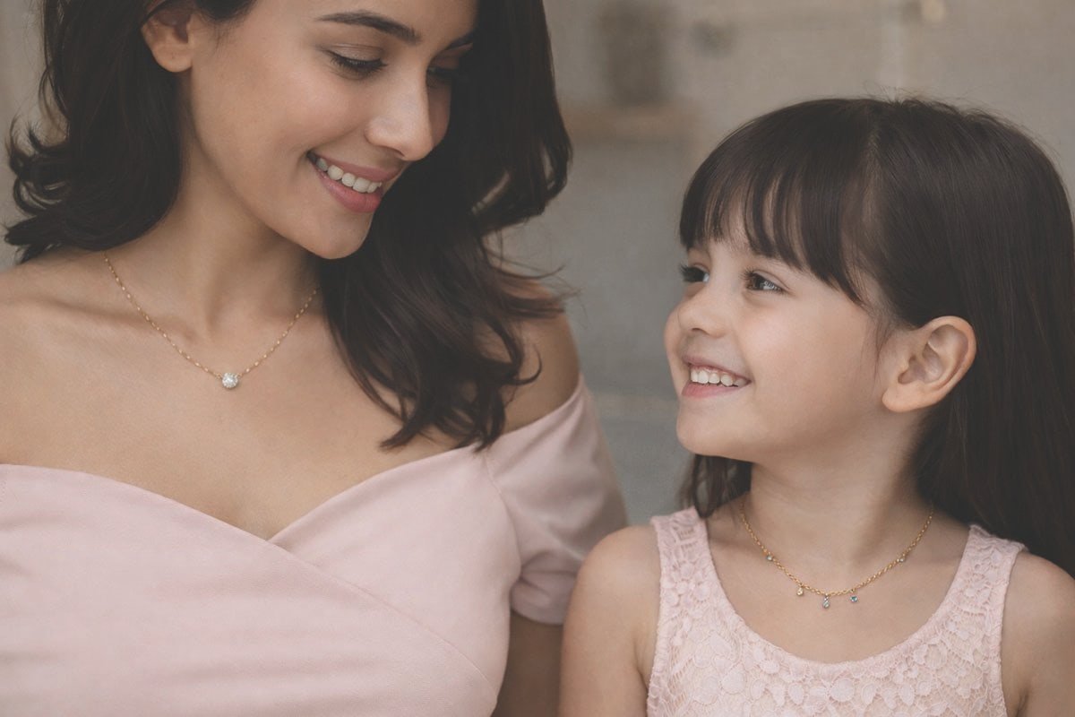 Mother and daughter smiling, showcasing delicate silver necklaces and jewelry.